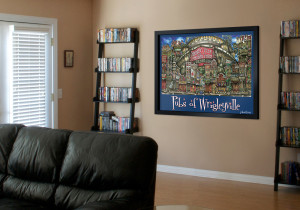 A living room with a black leather sofa, a matching shelving unit filled with books, and a colorful framed poster of "pubs of wrigleyville" on the wall.