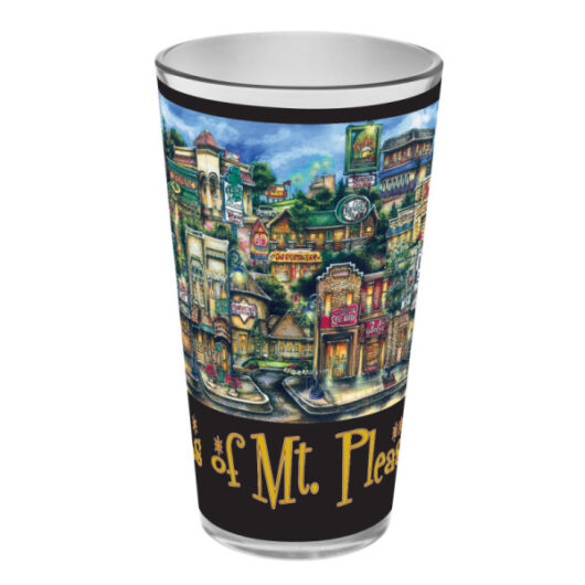 A colorful, illustrated pubsOf Mt Pleasant, MI Pint Glasses featuring a vibrant street scene with buildings, signs, and a clock, labeled "mt. pleasant.