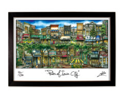 Framed artwork titled "pubs of town city" depicting a colorful street lined with various pubs and shops, featuring a stylized illustration.